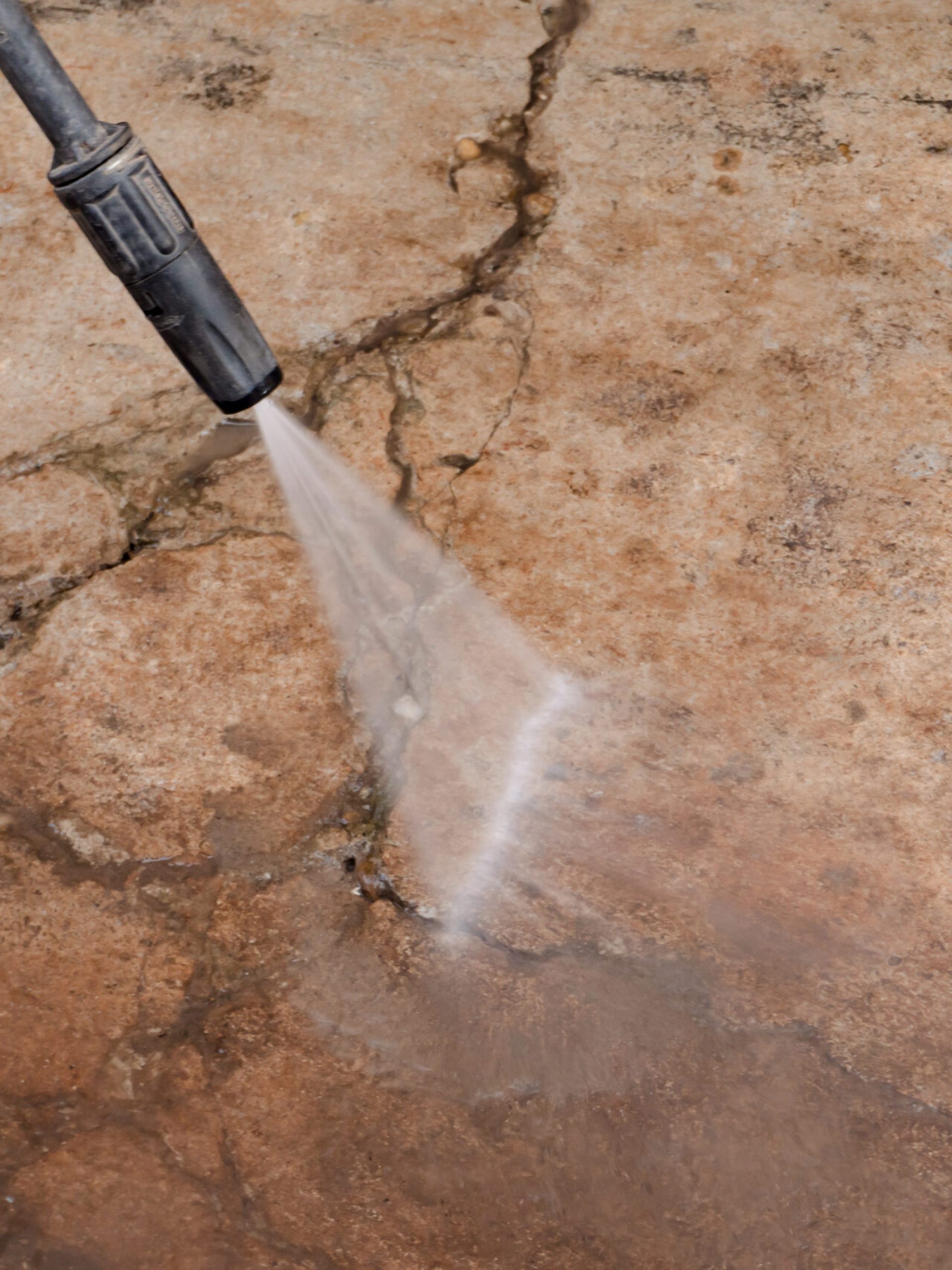 Worker cleaning dirty floor with high pressure washer